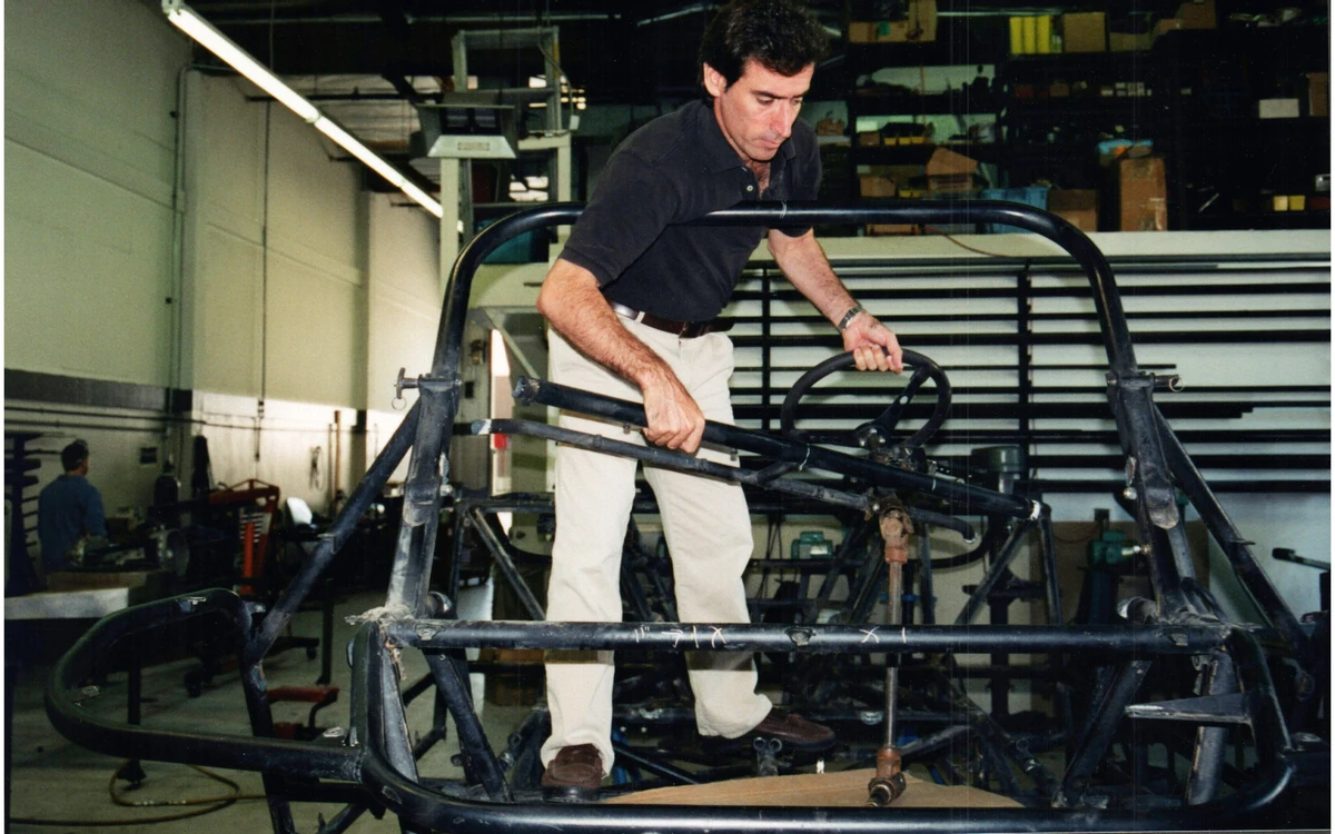 A person working inside a bare tubular vehicle frame