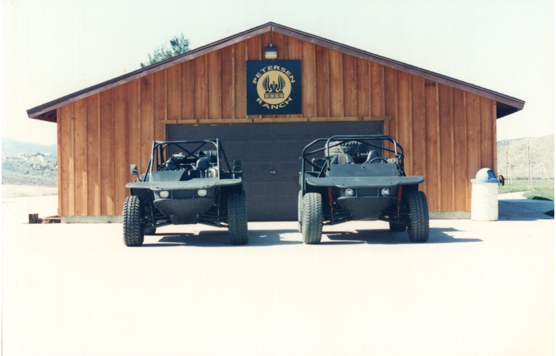 Two early Flyer vehicles parked in front of a Petersen Ranch building