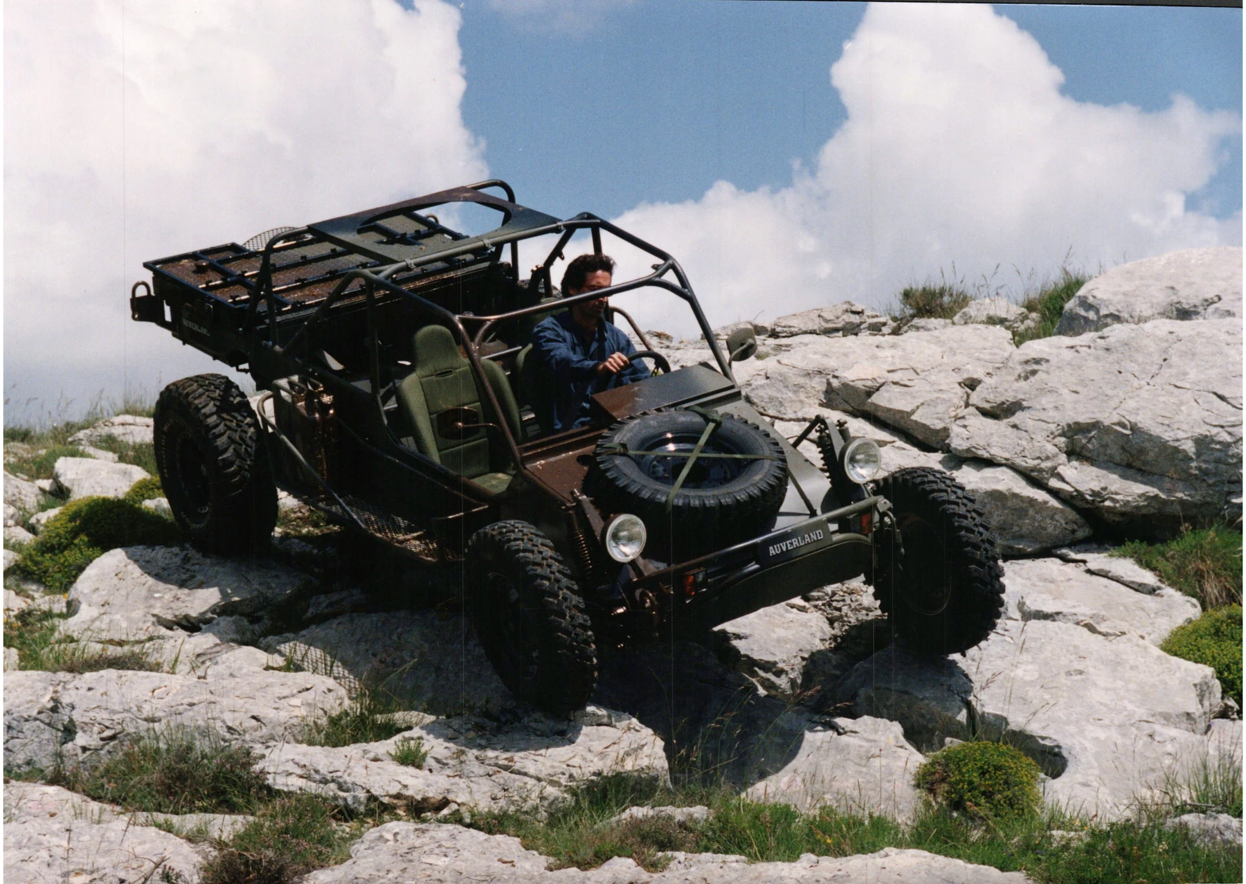 A lightweight open-cab vehicle negotiating a rocky landscape