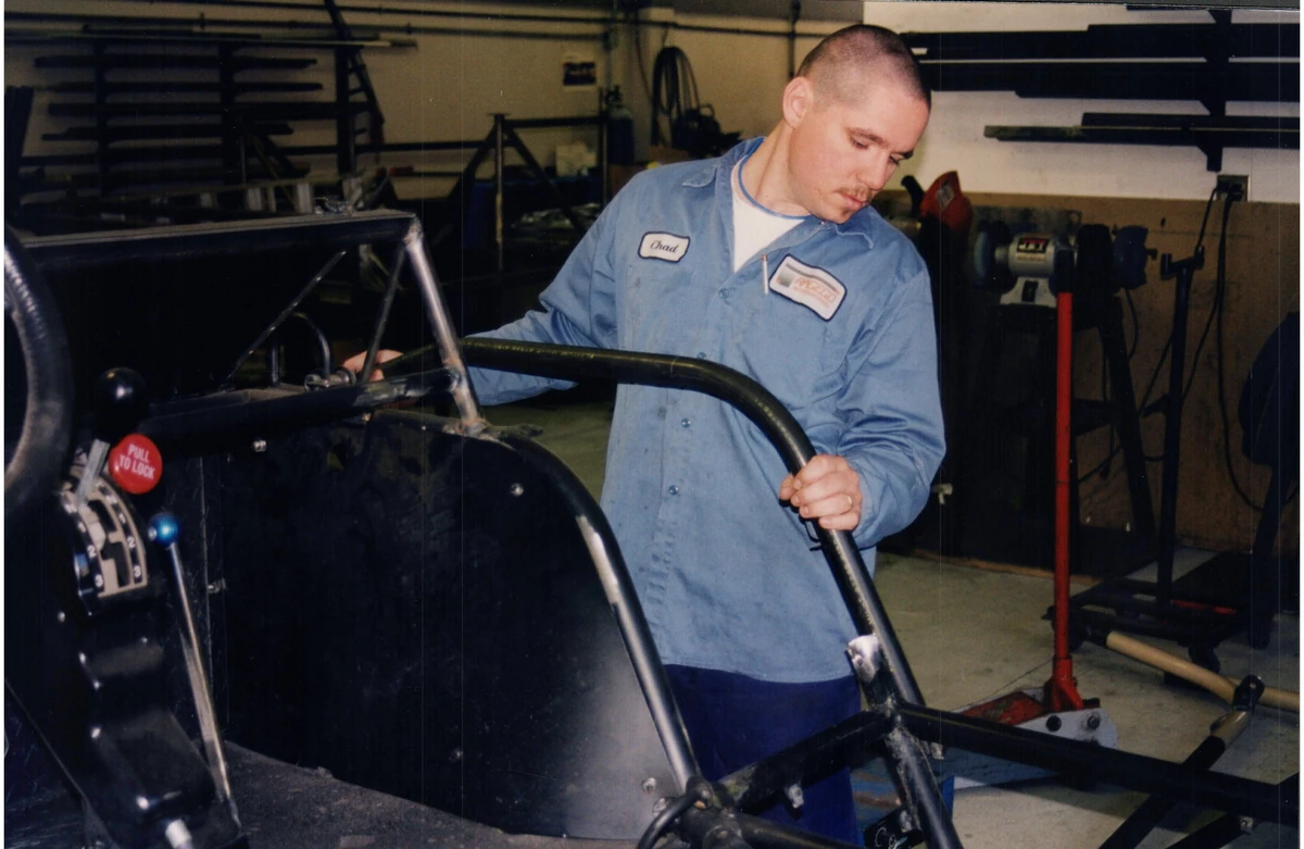 A technician working on the tubular structure of a Flyer vehicle in a workshop