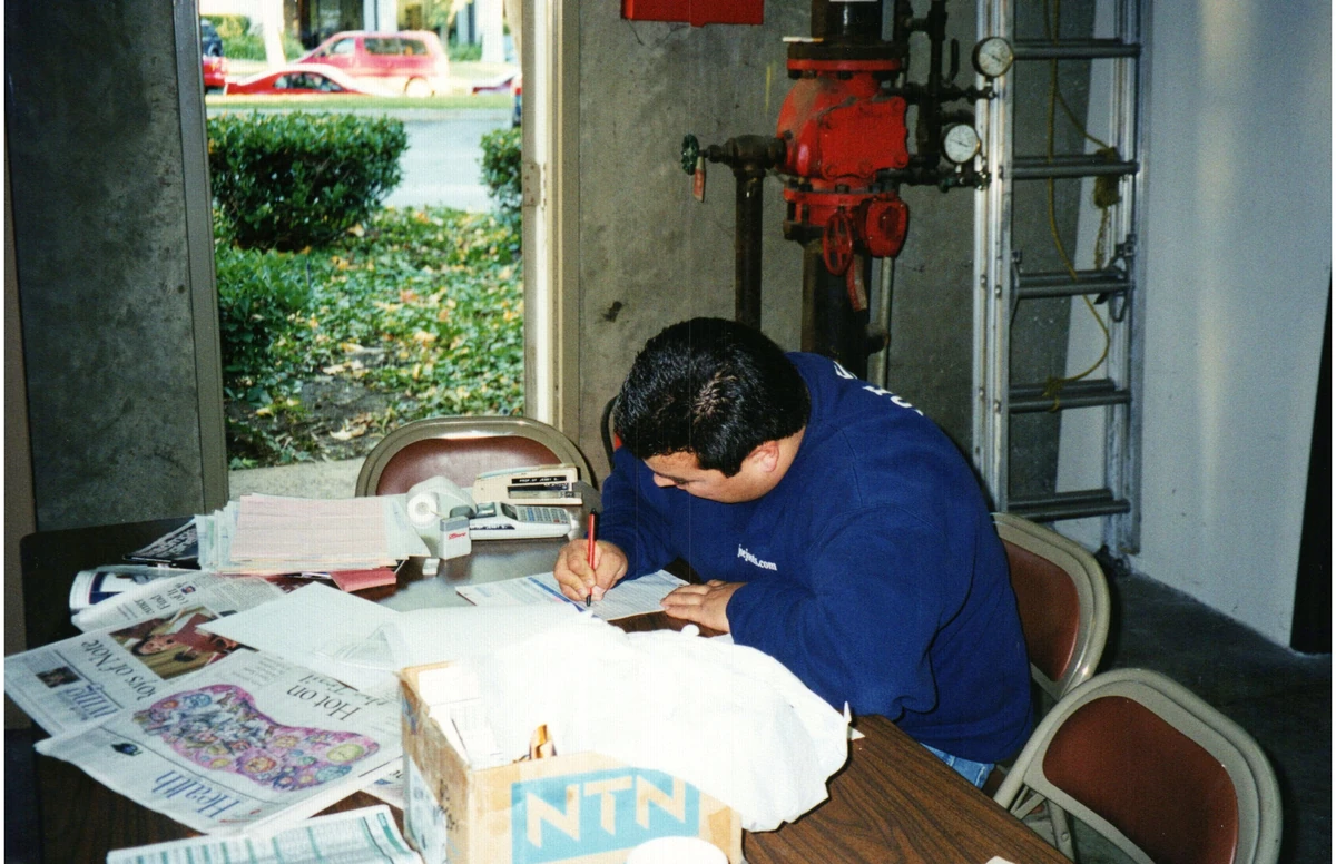 A person writing at a desk beside workshop equipment